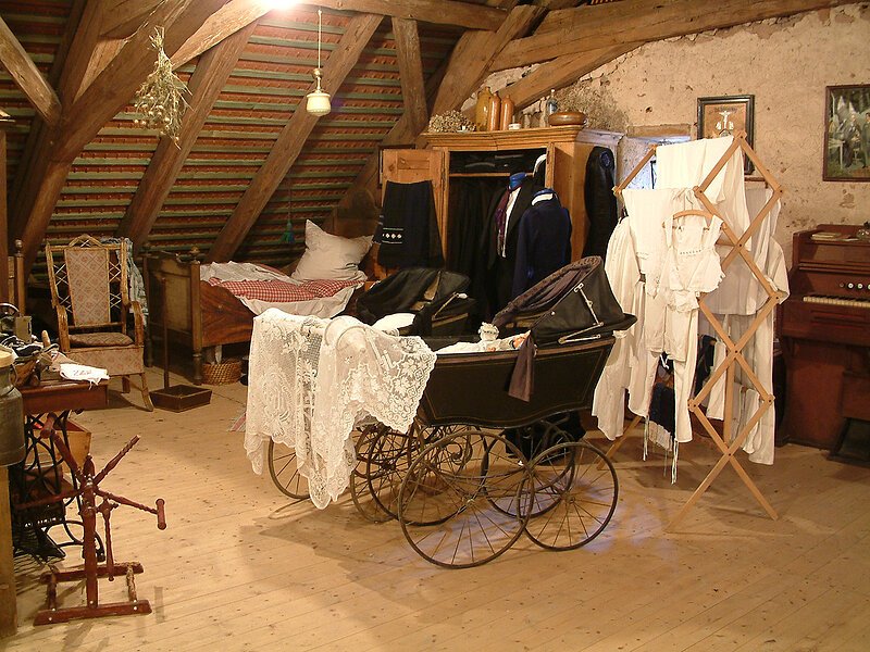 Foto Braun Gunzenhausen Ein alter Kinderwage und Klamotten stehen auf einem Dachboden, der als Museum ausgebaut ist.