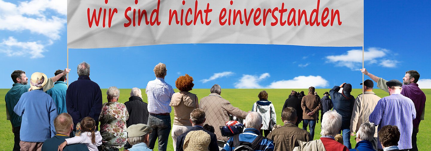 Ein Plakat mit Aufschrift "Wir sind dagegen" und die Dazugehörigen Demonstanten.
