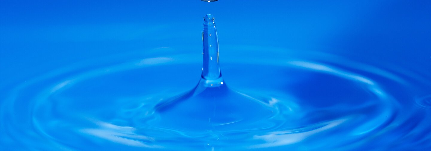 Springender Wassertropen, mittelblauer Hintergrund