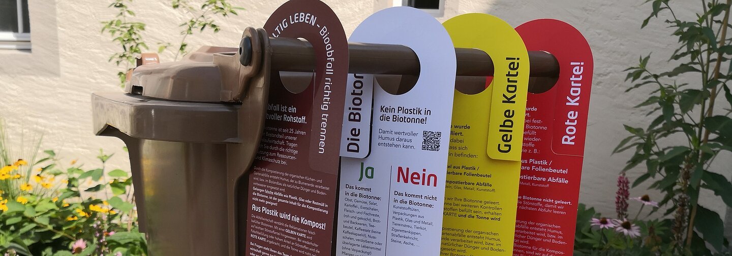 Biotonne mit vier Tonnenanhängern für richtig sortierte Bioabfälle zur Kompostierung, kein Plastik in die Biotonne, Verwarnung falsch befüllte Tonne Gelbe Karte, falsch befüllte Tonne Rote Karte - der Müll wird nicht geleert.