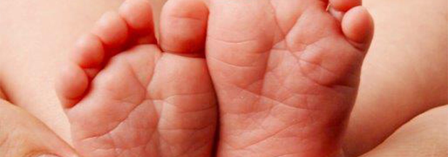 Babyfüße, die in Händen gehalten werden.