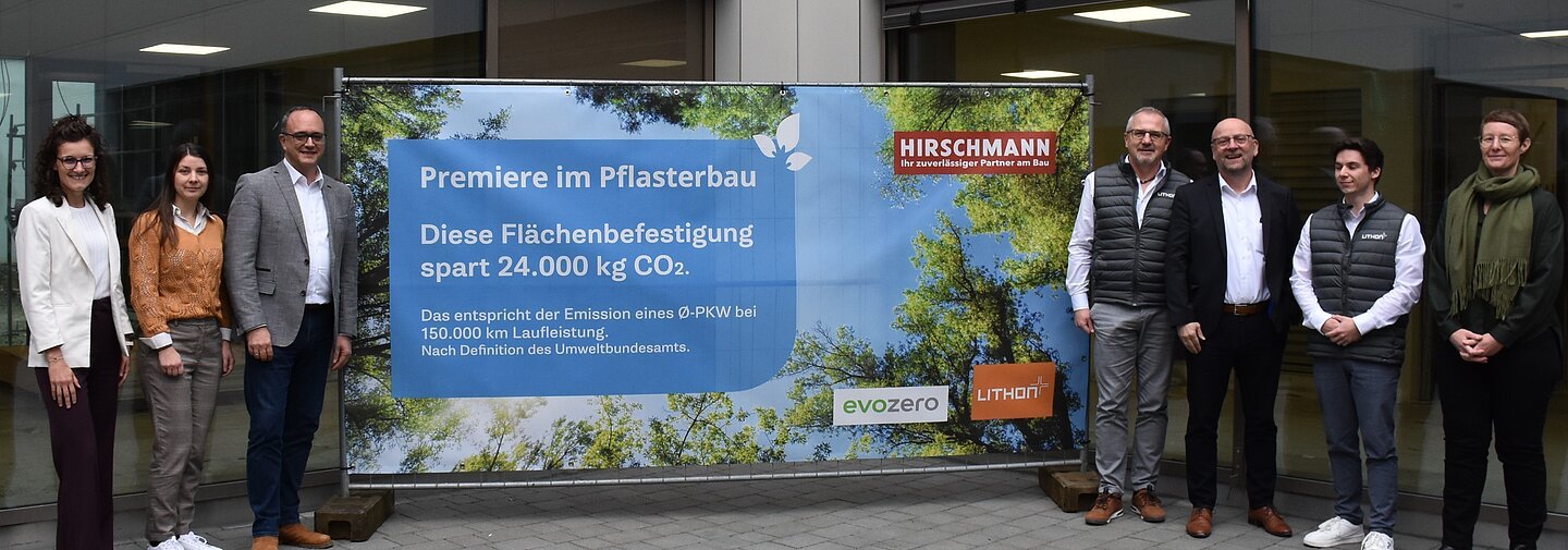 Eine Gruppe von Männern und Frauen steht neben einem Plakat, dass den Einsatz des neuen  evoZero-Zement bewirbt.