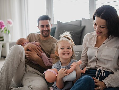 A happy young family with newborn baby and little girl enjoying time together at home.