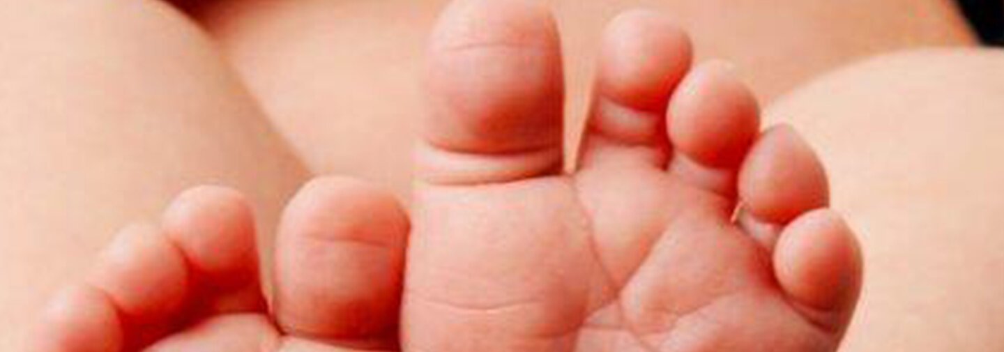 Babyfüße, die in Händen gehalten werden.