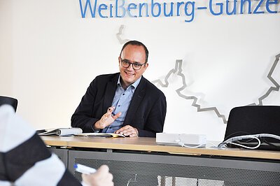 Landrat Westphal im Gespräch vor weißer Landkreiskarte