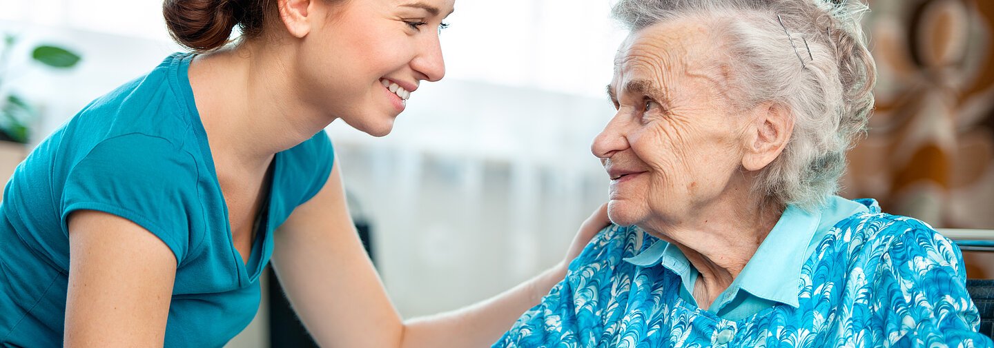 Senior woman with her caregiver at home - eine ältere Frau im Gespräch mit einer Pflegerin.